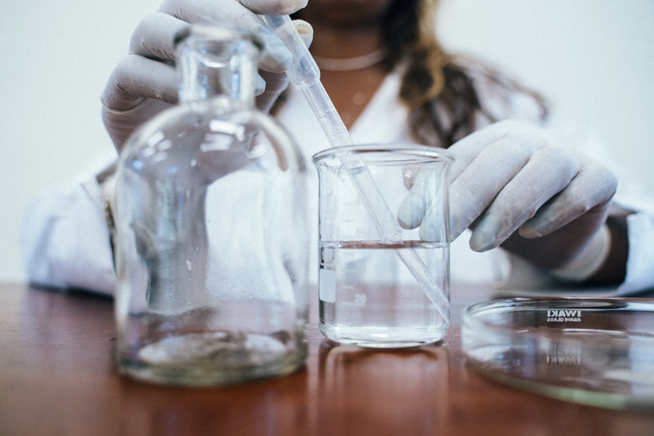 Close-up of a scientist using a dropper to add liquid to a beaker in the laboratory.